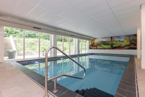 a large swimming pool in a house with windows at Fletcher Hotel Restaurant Erica in Berg en Dal
