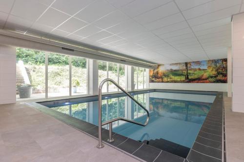 a large swimming pool with a staircase in a building at Fletcher Hotel Restaurant Erica in Berg en Dal