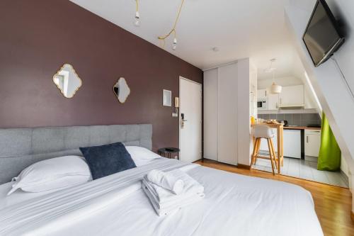 une chambre avec un grand lit blanc et une cuisine dans l'établissement 505- Charmant studio jardins des plantes -Paris 5 - FLAT-GUEST, à Paris