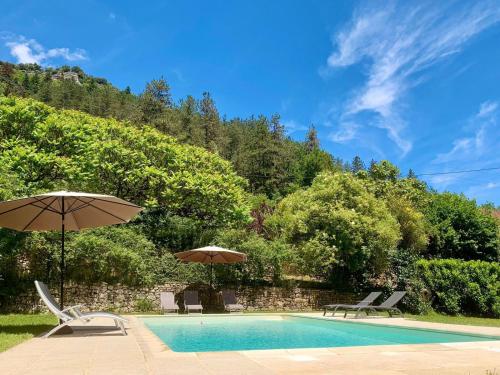 - une piscine avec 2 parasols et 2 chaises dans l'établissement Le Gîte du Pont de Cause, à Saint-Cybranet
