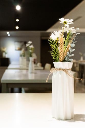 a white vase with flowers in it on a table at Talmud Hotel Kaohsiung LoveRiver in Kaohsiung