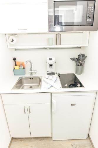 a white kitchen with a sink and a microwave at HEIMATEL - Suiten, Apartments und Studios in Scheidegg