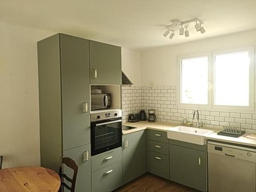 - une cuisine avec des placards gris, un évier et une table dans l'établissement Maison avec jardin à Figeac, à Figeac