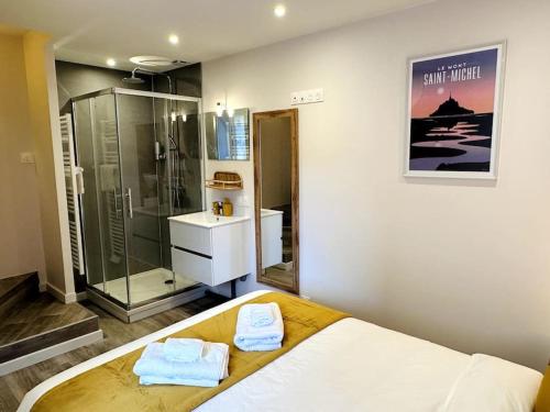 - une chambre avec une douche et un lit avec des serviettes dans l'établissement La Terre du Mont, à Avranches