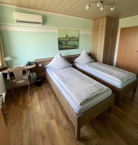 two beds in a room with a table and a desk at Gästezimmer zum Sonnenhof in Zahna-Elster