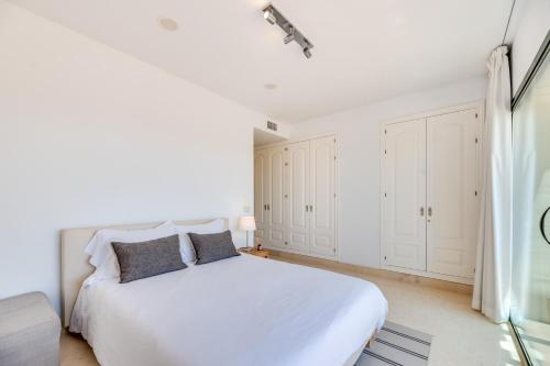 a white bedroom with a white bed and a window at Spacious 2-bed apt Capanes del Golf in Benahavís