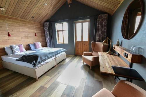 a bedroom with a bed and a couch and a chair at Fjalladýrð Guesthouse in Modrudalur