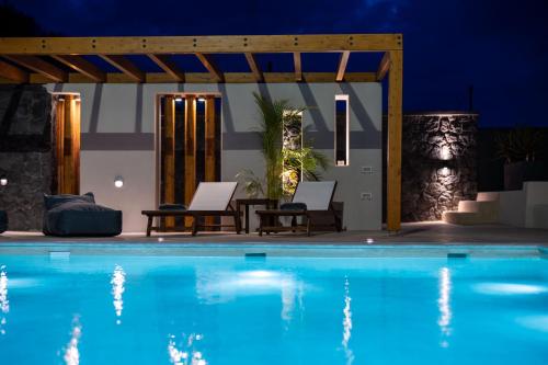 a pool at night with two chairs and a pergola at LyMaRou Collection in Megalokhori