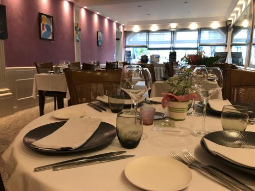 a table in a restaurant with white plates and glasses at Logis Hotel & Restaurant La Paix in Le Nouvion-en-Thiérache