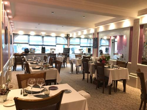 a restaurant with white tables and chairs and windows at Logis Hotel & Restaurant La Paix in Le Nouvion-en-Thiérache