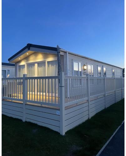 a house with a white fence on the grass at 59 Cliff Field in Hopton on Sea