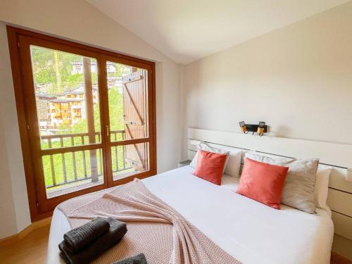 a bedroom with a bed with red pillows and a window at Ático De 3 Habitaciones Con Vistas Soldeu - Parking incluido l by BonesVacances in Soldeu