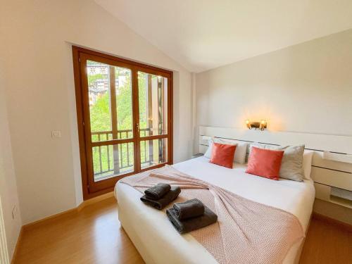 a bedroom with a large white bed with red pillows at Ático De 3 Habitaciones Con Vistas Soldeu - Parking incluido l by BonesVacances in Soldeu