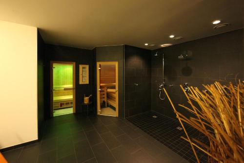 a bathroom with a shower with black walls and tile floors at Appartement Haus Sonne in Zell am See