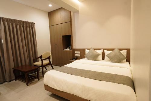 a hotel room with a bed and a chair at A Square Executive Hotel in Aurangabad