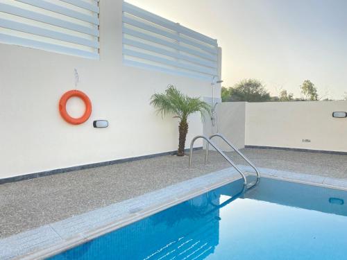 a swimming pool with a palm tree next to a white wall at Casa de Nicole in Protaras
