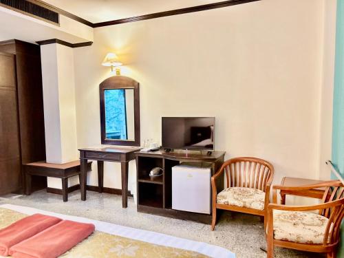 a room with a desk with a television and a table at Green House Hotel in Krabi town