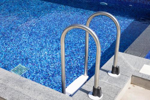 a swimming pool with metal rails next to a swimming pool at GardenVille Batumi in Batumi