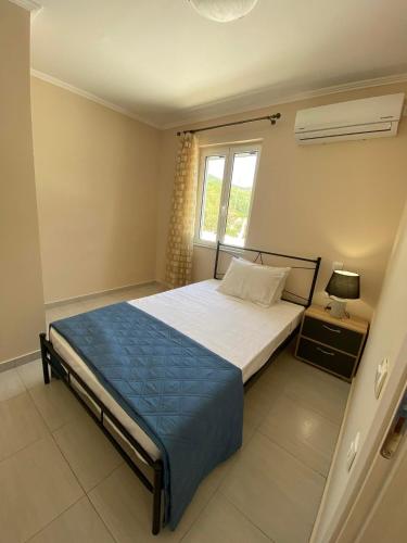 a bedroom with a bed with a blue blanket and a window at Sappir House in Pigadhákia