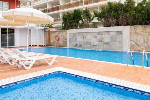 una piscina con dos sillas y una sombrilla en htop Summer Sun #htopEnjoy, en Santa Susanna