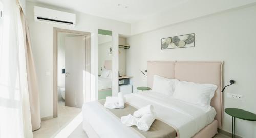 a white bedroom with a large bed and a mirror at ELA FIVE RESIDENCES in Athens