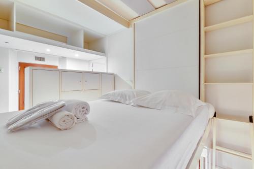 - un lit blanc dans une chambre avec des étagères dans l'établissement Marché Ordener - Appartement refait à neuf proche Montmartre, à Paris