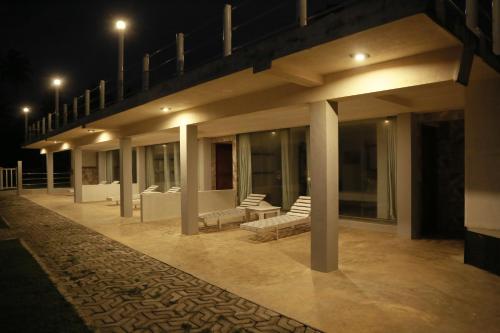 a building with chairs and tables on a patio at night at New Ocean Hill Hotel in Hikkaduwa