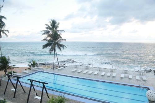 a swimming pool with a view of the ocean at New Ocean Hill Hotel in Hikkaduwa