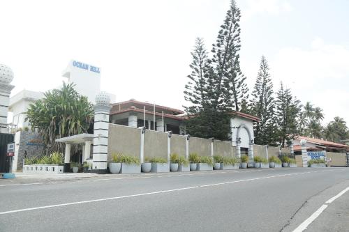 a street with a fence and trees and a building at New Ocean Hill Hotel in Hikkaduwa