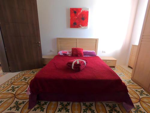 a bedroom with a red bed with a red blanket at Charming Townhouse - Steps from Waterfront in Marsaxlokk