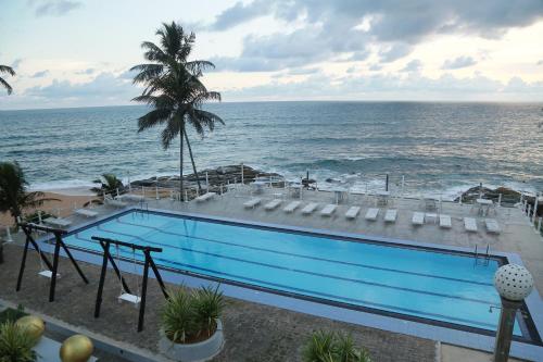 a swimming pool with a view of the ocean at New Ocean Hill Hotel in Hikkaduwa