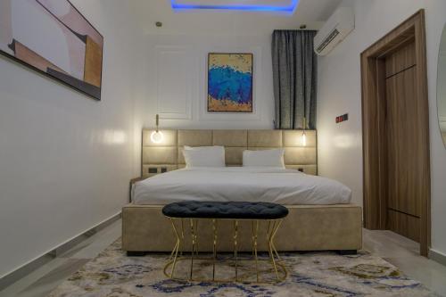 a bedroom with a large bed and a stool at One90 Apartment in Lagos