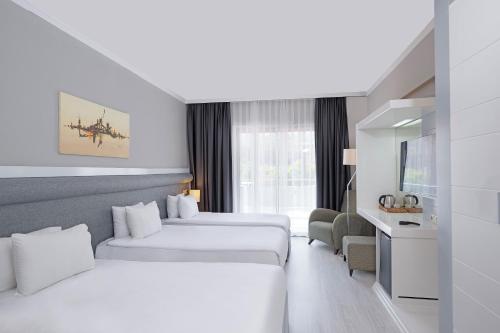 a hotel room with two beds and a tv at Dedeman Kemer Resort - Ultra All Inclusive in Kemer