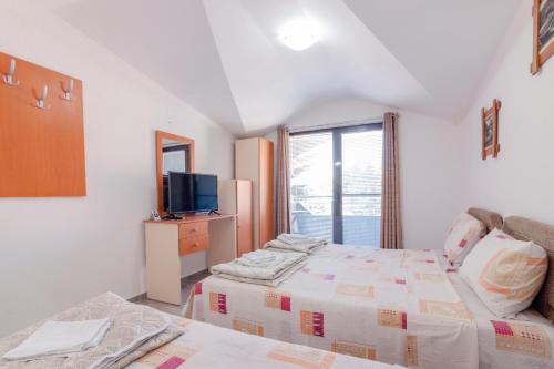 a bedroom with two beds and a tv and a window at Villa Ljupce in Ohrid