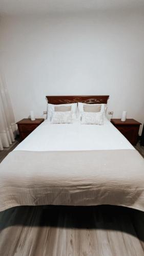 a bedroom with a white bed with two night stands at Piso BOIRO PLAYA Robustiano in Boiro
