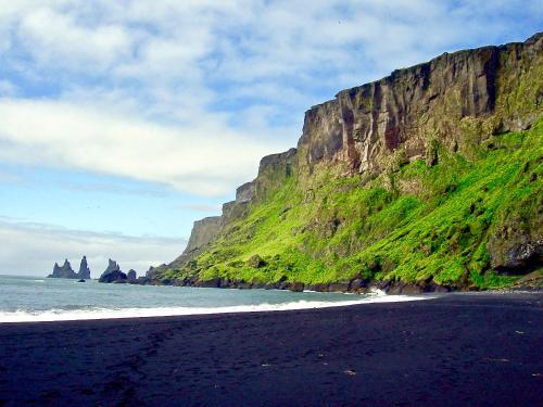 a black sand beach with a mountain in the background at Hrossholt in Stykkishólmur