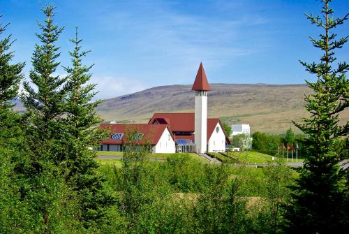 a white church with a red roof and a tower at Hrossholt in Stykkishólmur