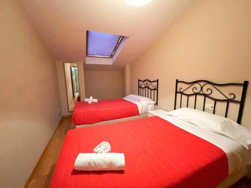 a bedroom with two beds with red sheets and a skylight at Alojamientos Barreiros 3000 in Barreiros