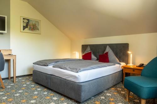 a bedroom with a bed and a blue chair at Hotel Restaurant Ancho in Cölbe