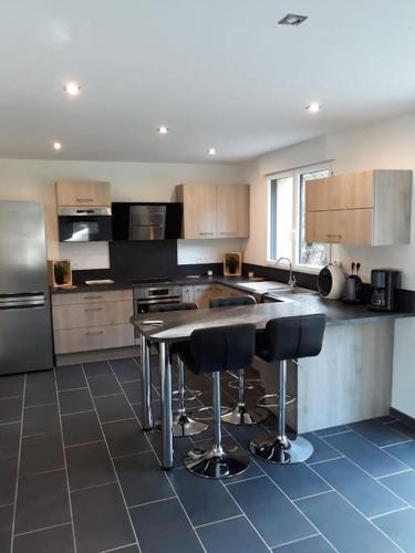 - une cuisine avec un îlot doté de tabourets de bar dans l'établissement Charmante maison, proche de DEAUVILLE, à Saint-Étienne-la-Thillaye