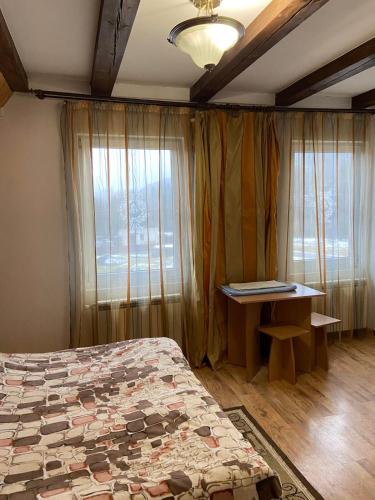 a bedroom with a bed and a desk and a window at Садиба у Віталія in Volovets