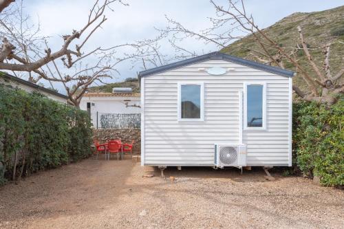 a small white tiny house sitting in a yard at Falaguera Bungalow 1 in Bárig