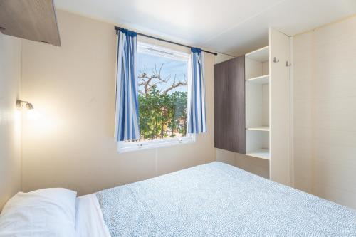a bedroom with a bed and a window with blue curtains at Falaguera Bungalow 1 in Bárig