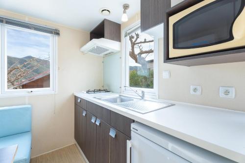 a kitchen with a sink and a tv on the wall at Falaguera Bungalow 1 in Bárig