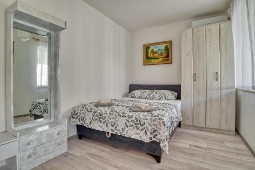 a bedroom with a bed and a mirror at Baka Zlata Apartments in Petrovac na Moru