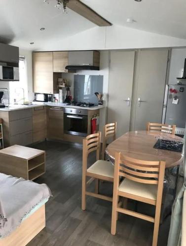 Il comprend une cuisine avec une table et des chaises en bois. dans l'établissement Mobile Home avec piscine dans Camping calme Proche plage, à Saint-Hilaire-de-Riez