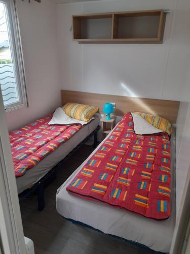 deux lits côte à côte dans une pièce dans l'établissement Mobile Home avec piscine dans Camping calme Proche plage, à Saint-Hilaire-de-Riez