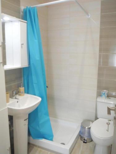 a bathroom with a blue shower curtain and a toilet at Bright Sea - Studios in Limenas