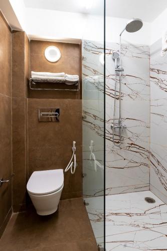 a bathroom with a toilet and a glass shower at Pema Thang Guest House Mcleodganj in Dharamshala