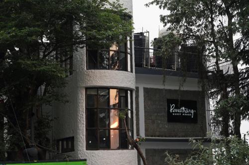 a building with a sign on the side of it at Pema Thang Guest House Mcleodganj in Dharamshala